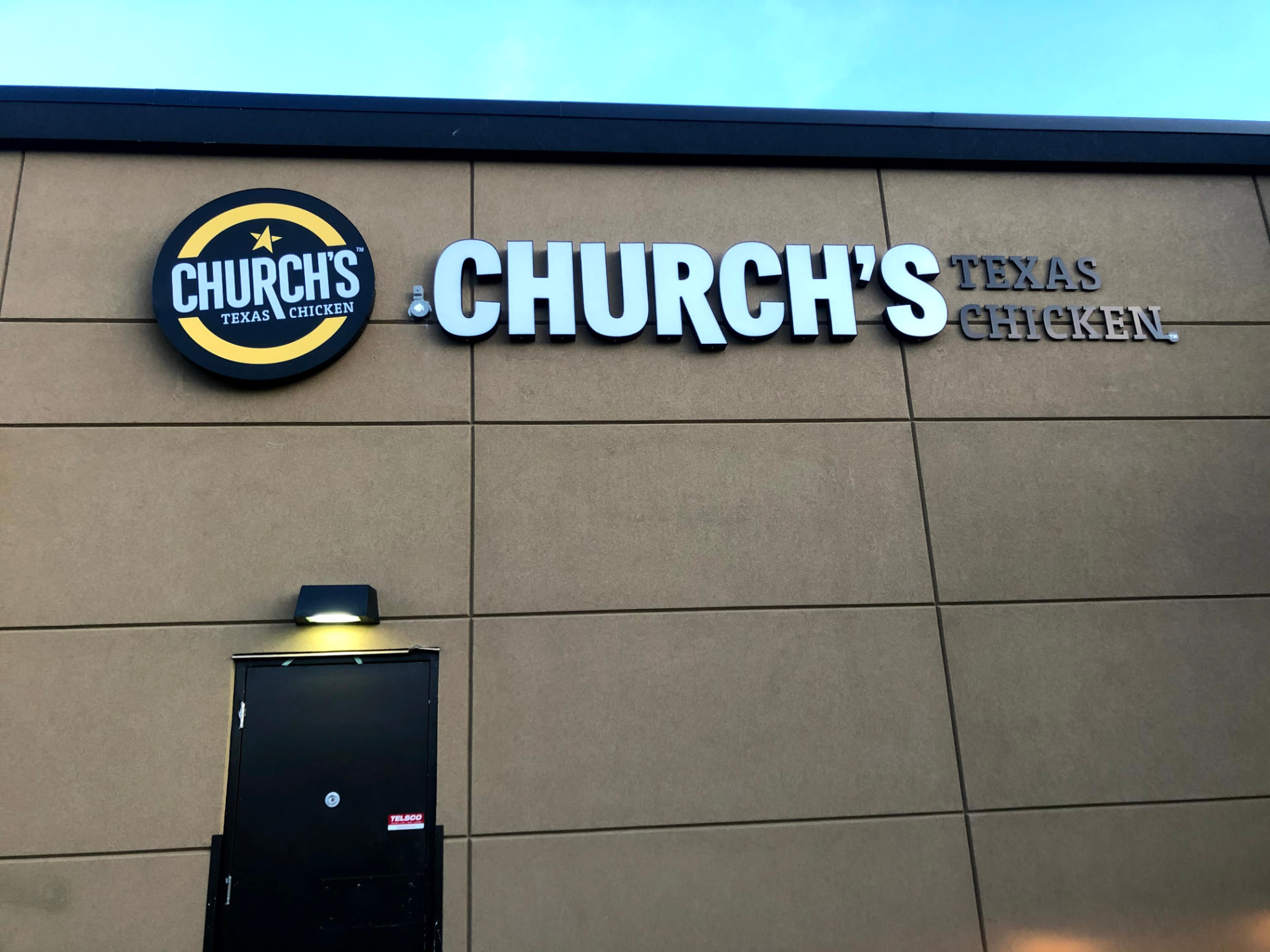 Church's Texas Chicken illuminated channel letters beside a lit logo cabinet